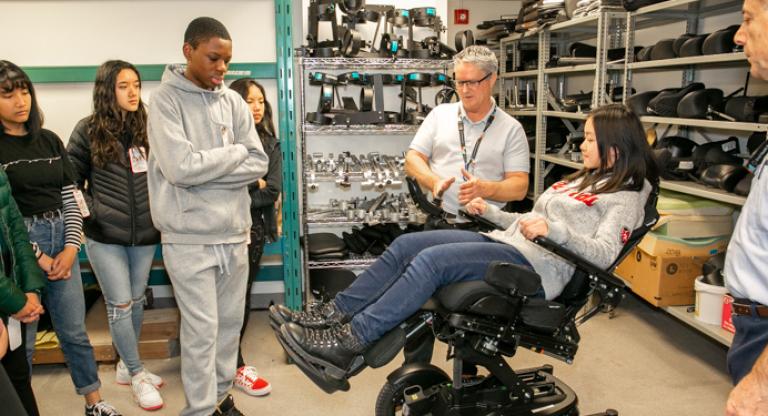 Children examining motorized chair with Sinai Health employees. 
