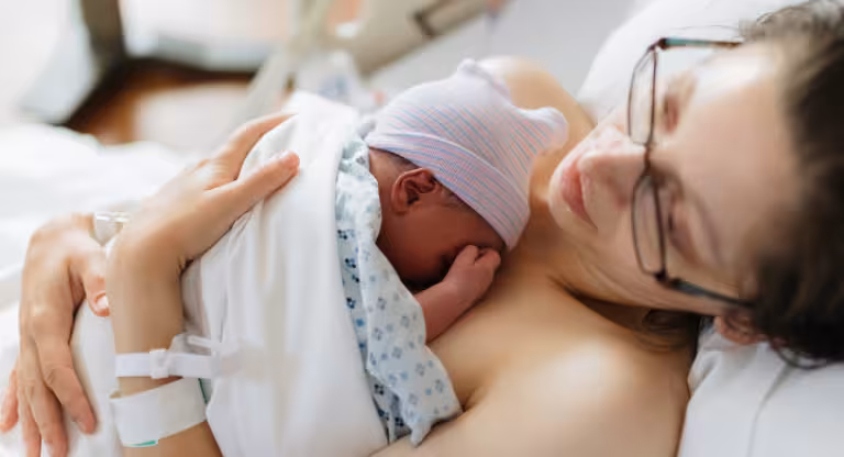 Mother holding her newborn baby in hospital bed