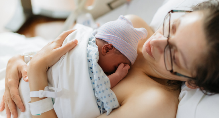 Mother holding her newborn baby in hospital bed