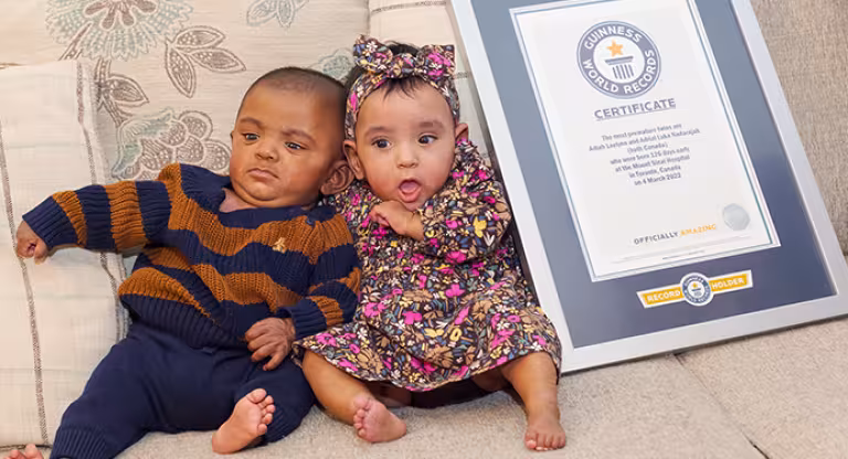 The world’s most premature twins sitting on a sofa next to their Guinness Record Certificate