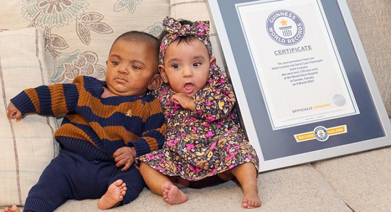 The world’s most premature twins sitting on a sofa next to their Guinness Record Certificate