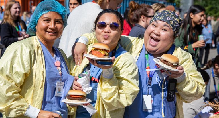 Sinai Health staff members wearing scrubs and holding burgers on paper plates at the staff appreciation bbq