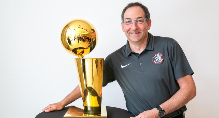 Dr. Howard Petroff posing next to the Larry O'Brien NBA Championship Trophy