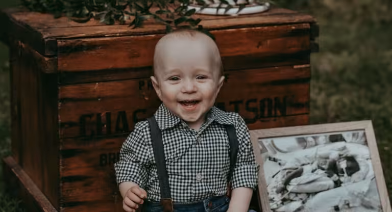 Little boy sits next to black and white photo