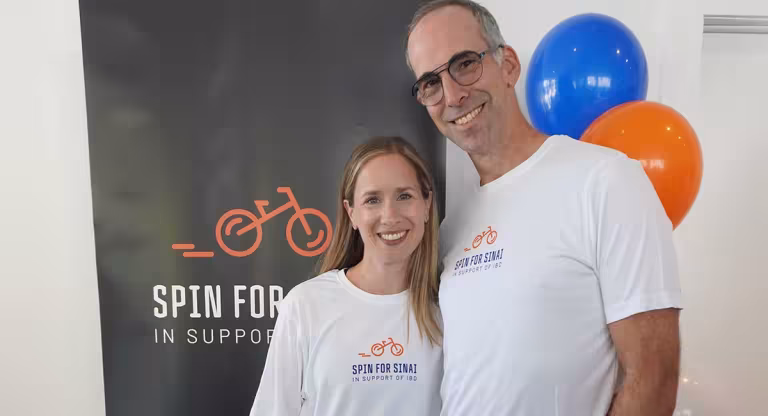 man and woman stand in front of banner and balloons 