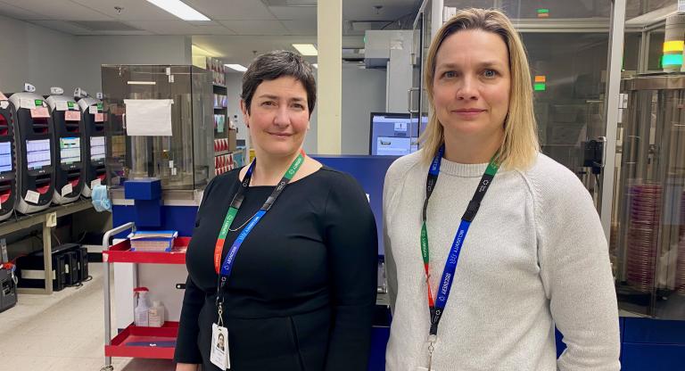 A phone of Dr. Anne-Claude Gingras beside Dr. Jennie Johnstone in the lab. 