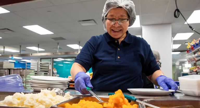 Staff member at Mount Sinai Hospital in the new revamped kitchen. The staff member is serving food 
