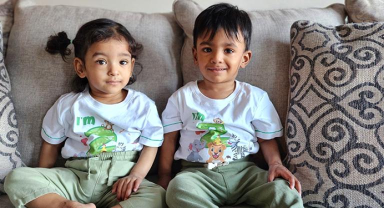 A photo of the world's most premature twins setting beside each other on a couch.