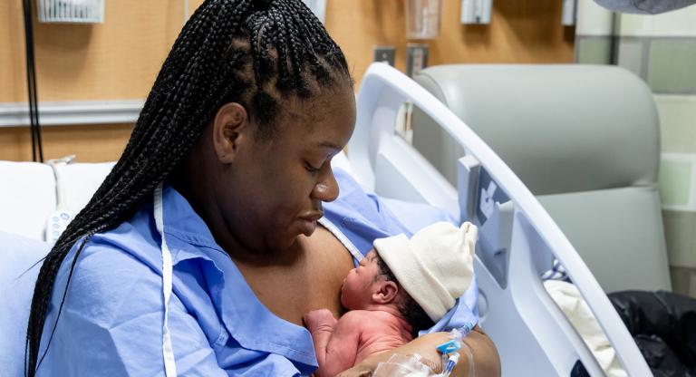 New mother holding her baby in a hospital bed.