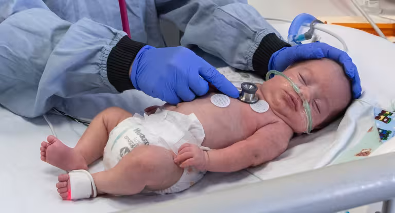 Nurse examining preterm baby with a stethoscope.