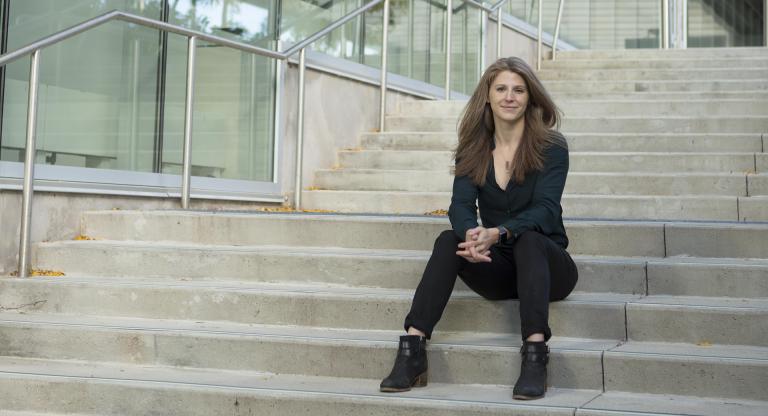 Woman sitting on the steps outside a glass-walled building