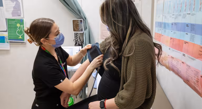A visibly pregnant woman receiving care from a health-care professional