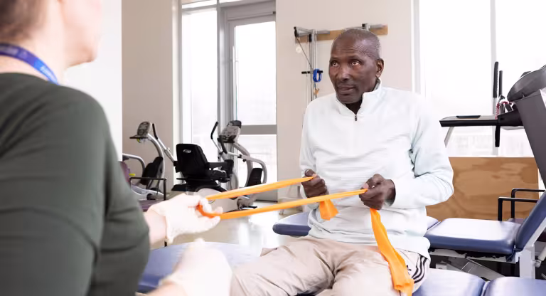 Mr. Solomon using yellow bands during rehab session.