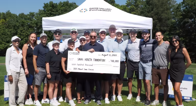 group stands outside holding presentation cheque