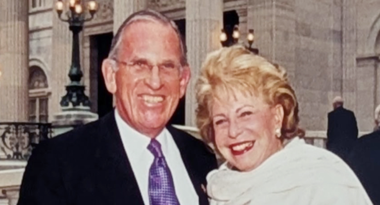 Smiling man and woman. Red banner with white text reads Jerry and Carole Grafstein