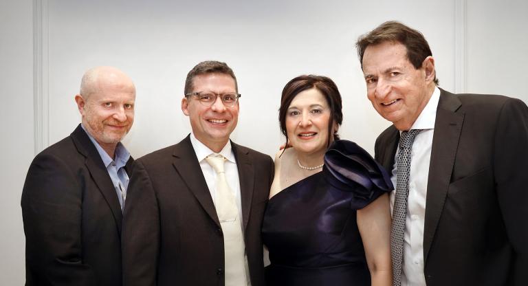 three men and one woman stand smiling