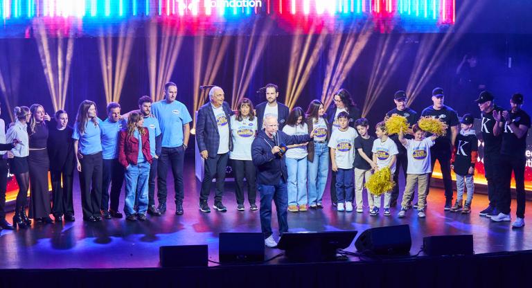 large group stands on stage, celebrating their win