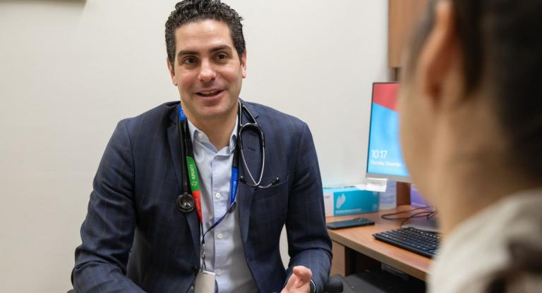 Dr. Nathan Stall, Geriatritician, Clinician Scientist and Geriatrics Site Lead at Sinai Health, sits with a patient in an exam room at Mount Sinai Hospital.