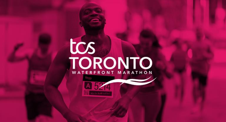 A man smiling while running in a marathon with the white logo that says TCS Toronto Waterfront Marathon