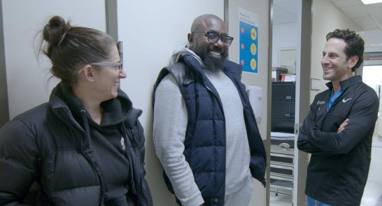 three people stand in hospital hallway