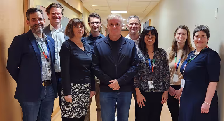 A team of researchers from Sinai Health and the University of Toronto standing in a hallway together smiling. 