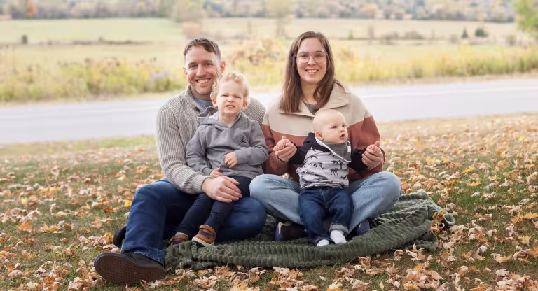 family sits on a blanket in a field