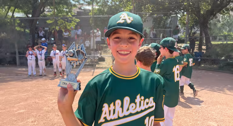 young baseball player holding trophy