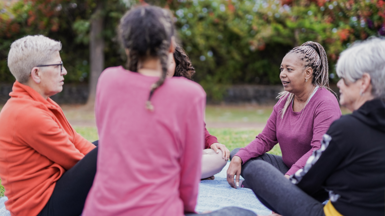 A group of women seated in a circle outside.