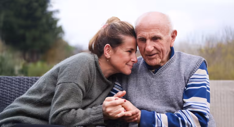 Adult woman holding older father outside