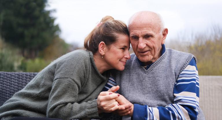 Adult woman holding older father outside
