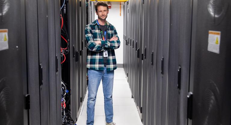 a while man wearing jeans and shirt standing in a server room