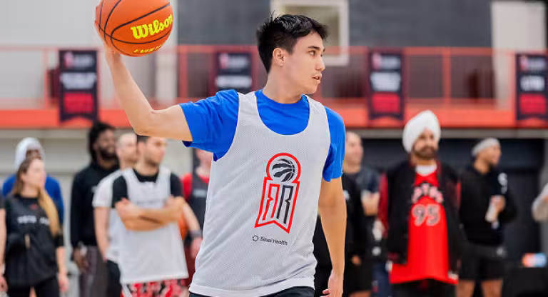 Young man wearing a jersey prepares to pass a basketball on an indoor court