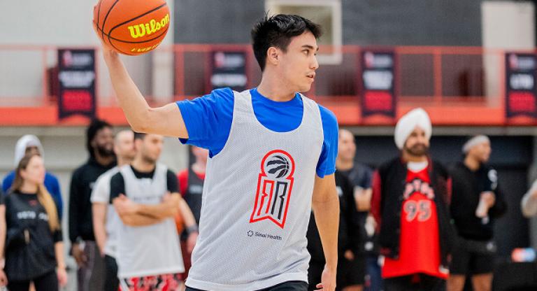 Young man wearing a jersey prepares to pass a basketball on an indoor court