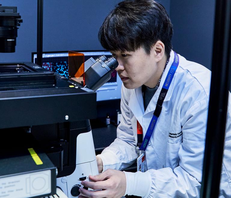 Researcher looking through a computerized microscope