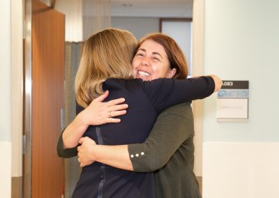 Manuela Ocrainschi receiving a hug and thanks from Minister Elliott