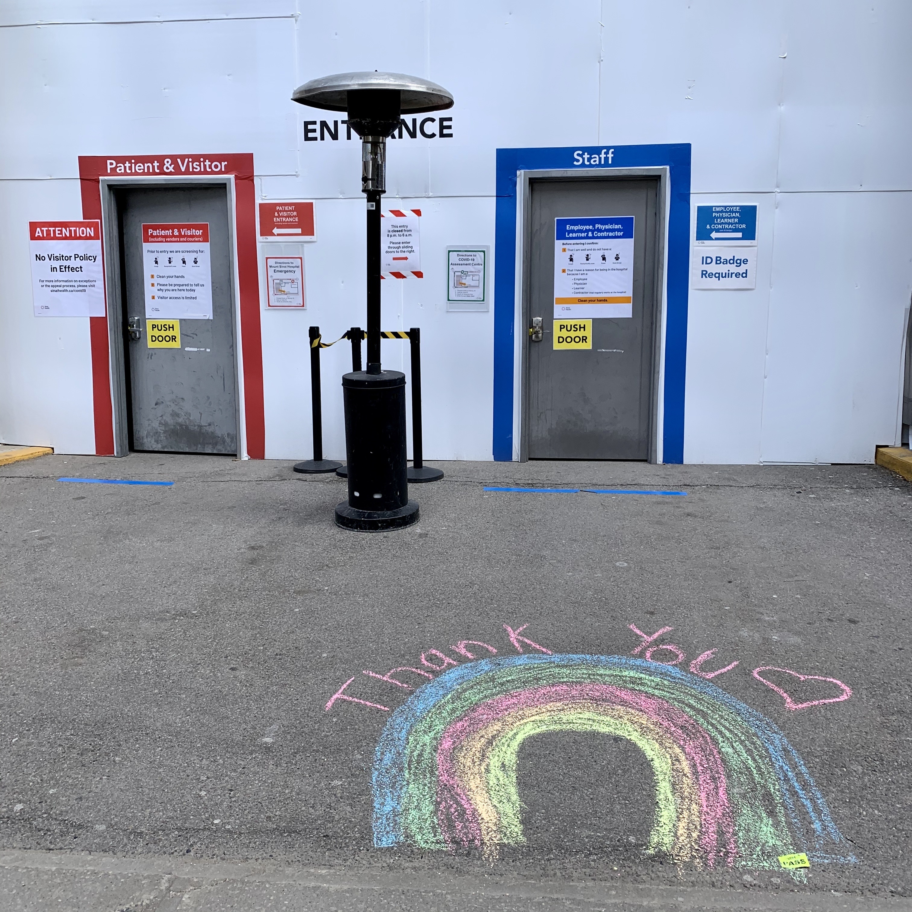 The hospital entrance with a rainbow and the words Thank You drawn on the pavement in front of the doors