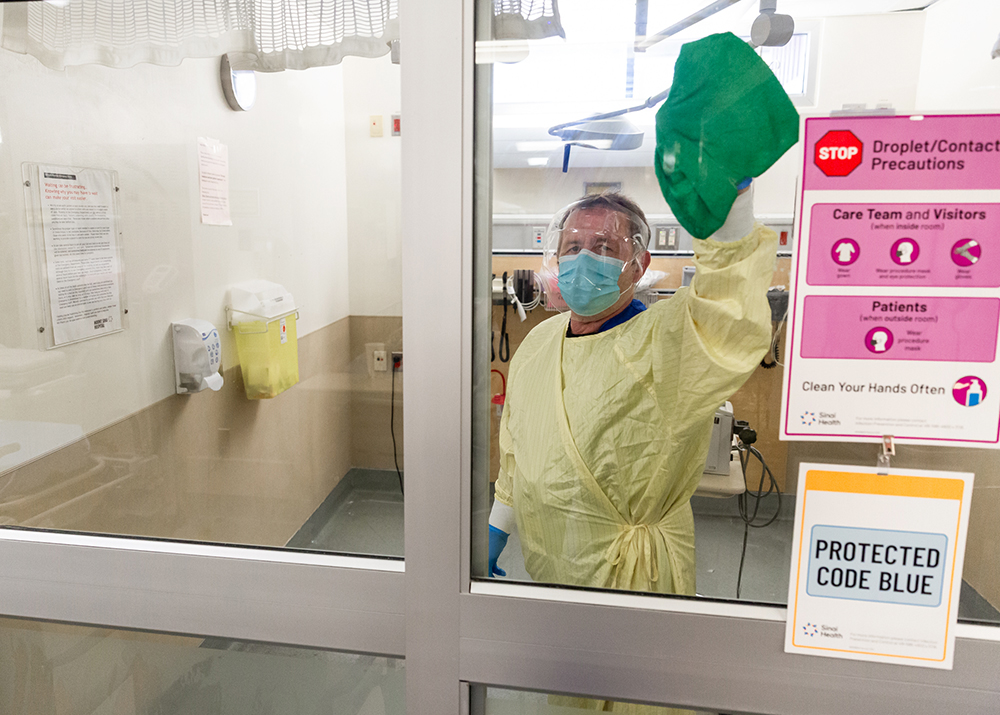 Clinical service assistant cleaning a window in a clinical care area