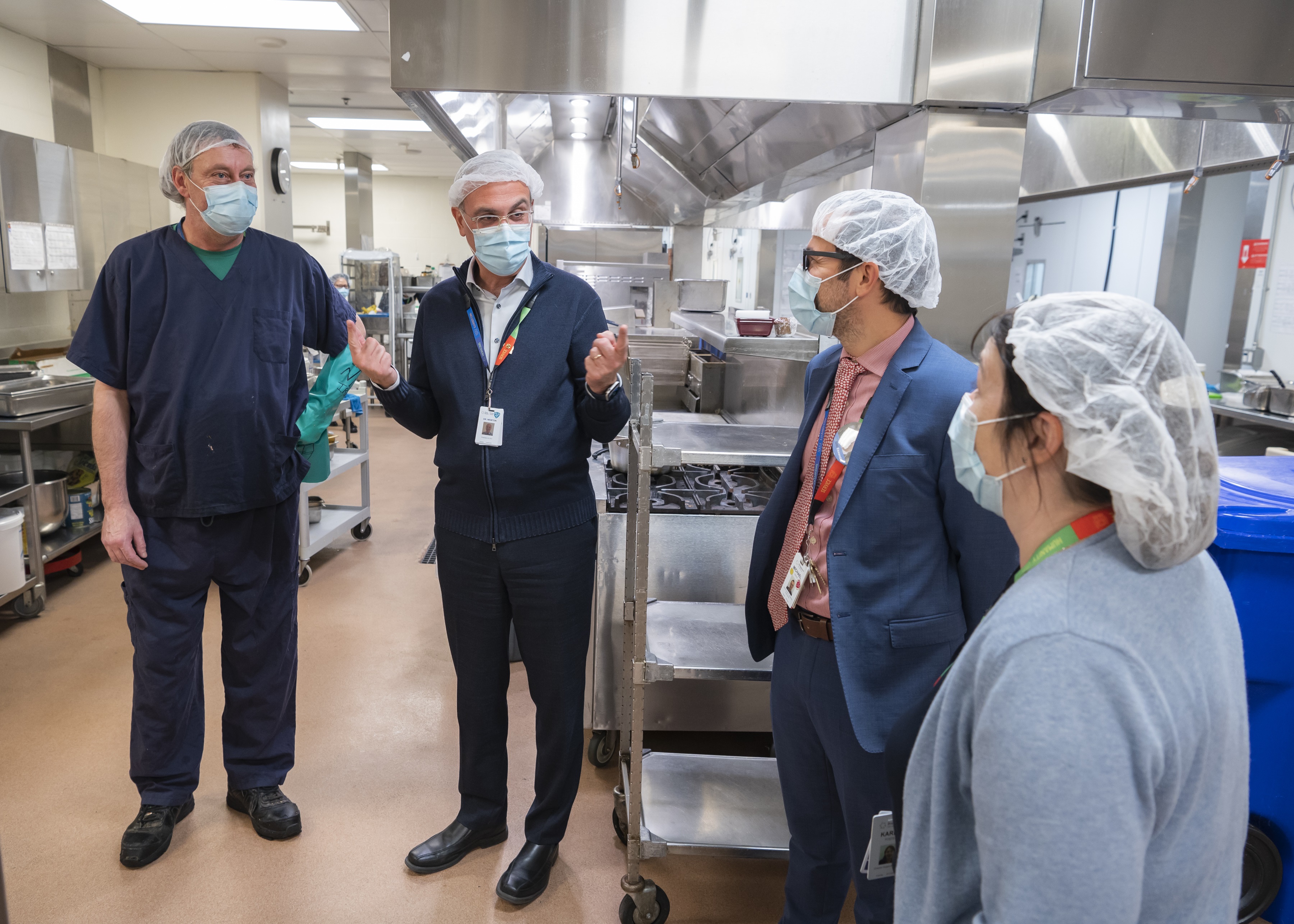 Dr. Gary Newton talks with employees in the Food Services kitchen at Hennick Bridgepoint Hospital