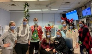 a group of people from the switchboard and locating Department at Mount Sinai Hospital. They are wearing holiday-themed clothes and accessories like reindeer antlers and garlands.